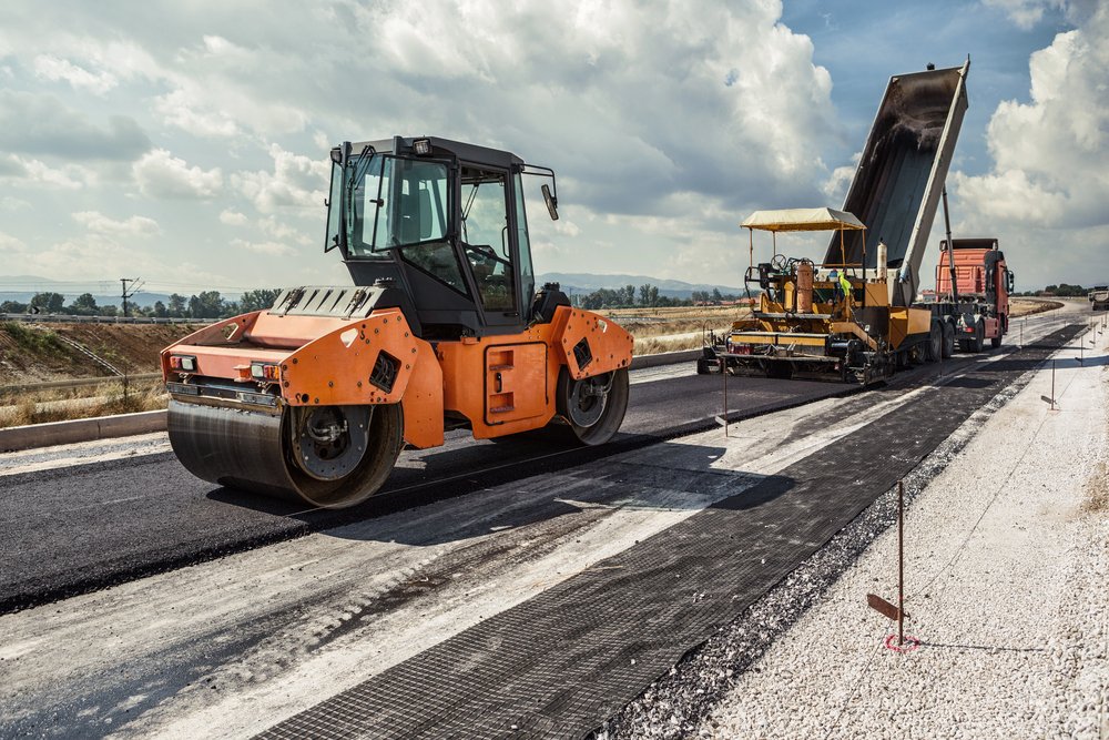 Road crew paving fresh asphalt with a roller and paver