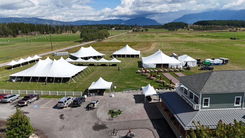 Aerial view of white event tents on a field with mountains on the horizon