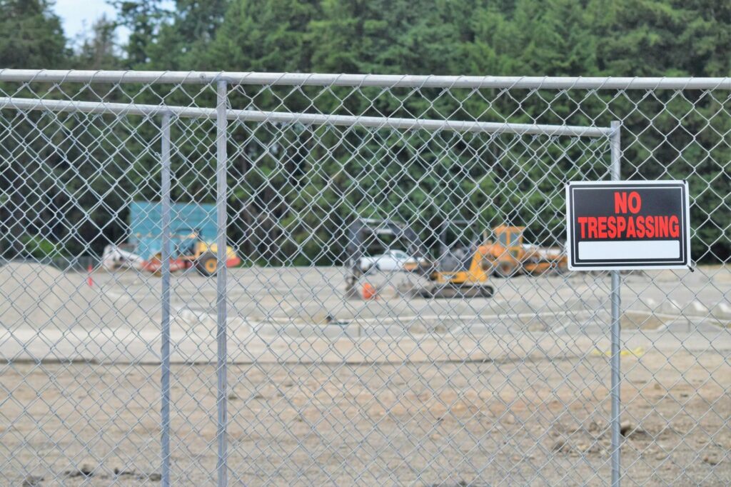 Temporary chain-link fence panels around a construction site with an excavator inside