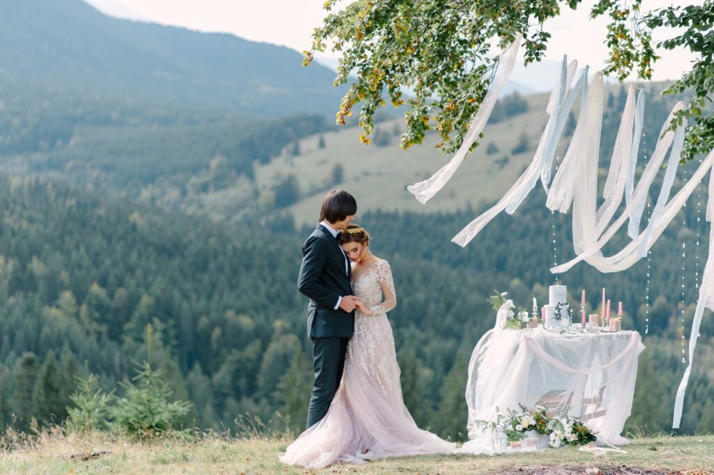 Couple at an outdoor mountain wedding with a forested valley behind them